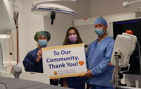 Team members hold up a sign thanking the community for their support.