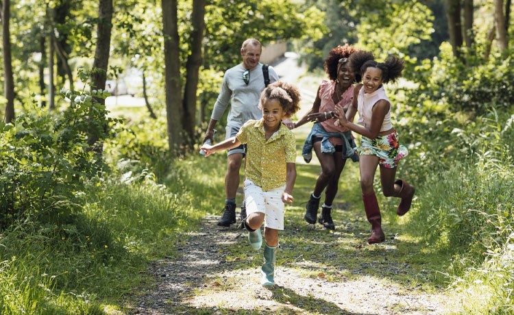 A young family enjoys a hike through a sun-dappled woods.