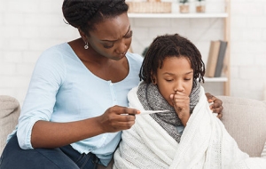 Mom feels forehead of child with a fever.