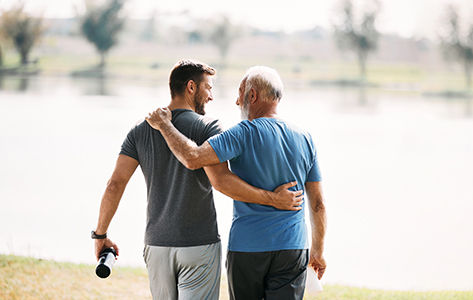 A father and son embrace on a sunny day.