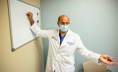 Naeem Rahman, M.D. presents at a whiteboard.