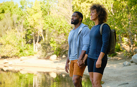 a man and a women stop to admire a stream while hiking