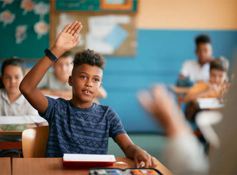 A child raises his hand in a classroom.
