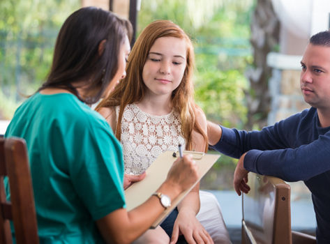 A teen girl meets with a mental health provider.