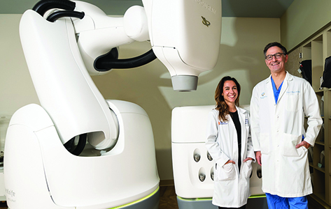 Doctors Joana Emmolo and Yaron Moshel in front of the CyberKnife technology