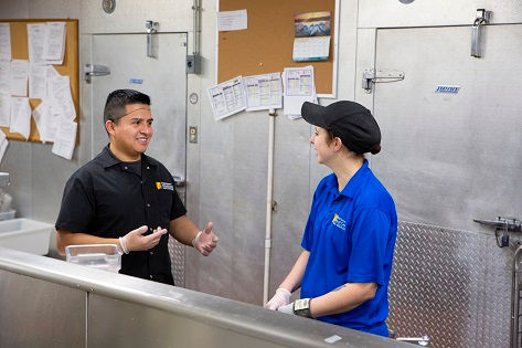 Two support service staff members smile at each other.