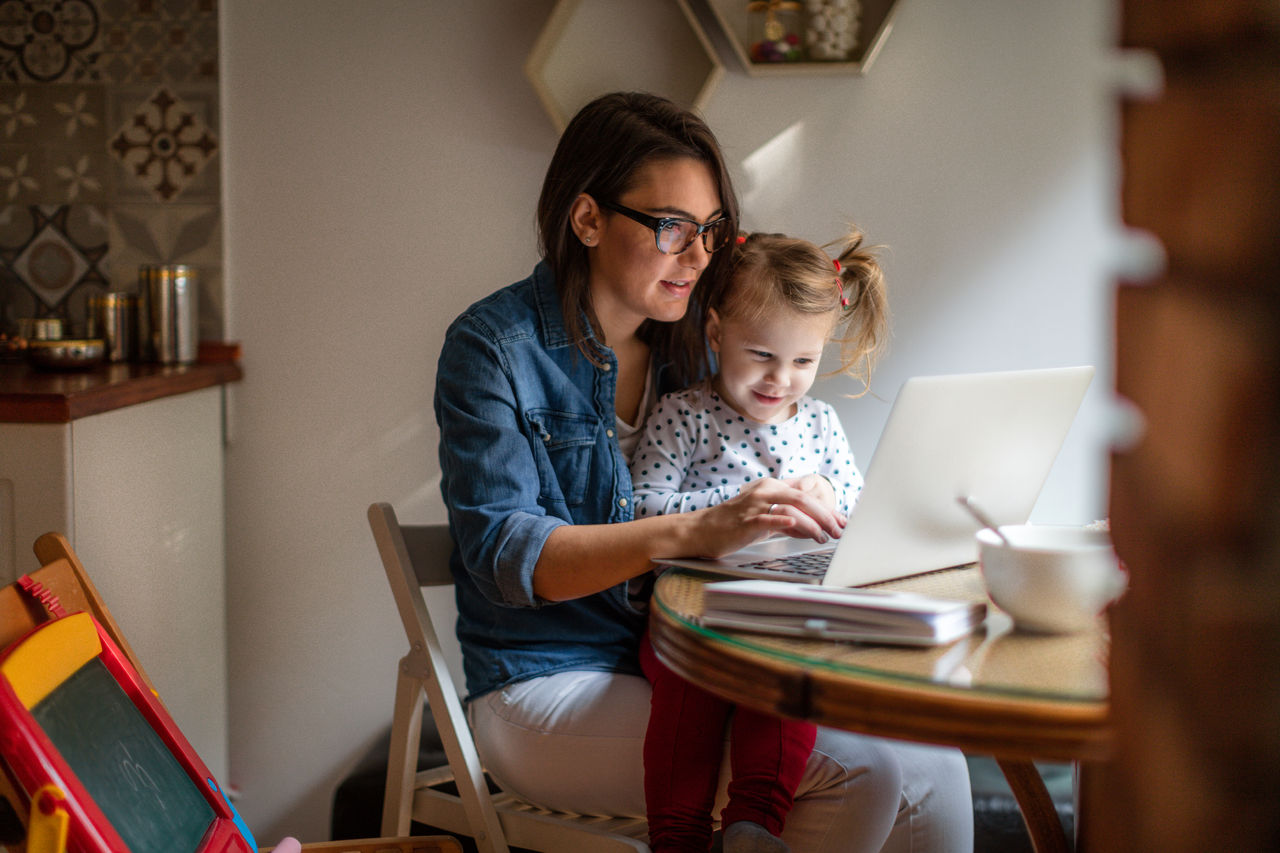 A young woman and her daughter search related links on a laptop.