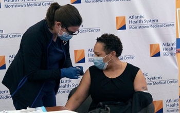 Nurse administers COVID-19 vaccine to woman.