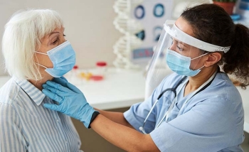 A doctor examines a patient as she recovers from COVID-19.