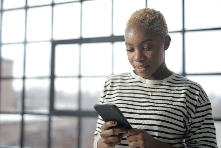 Young woman uses her cellphone to educate herself about COVID-19.