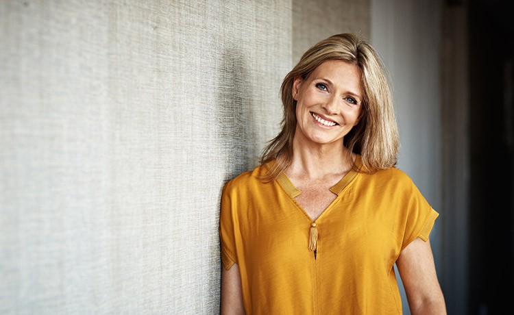 Smiling woman leaning against a wall