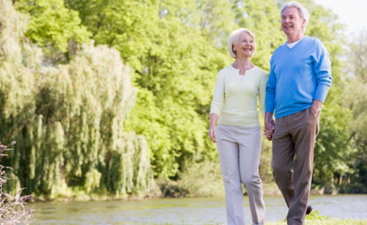 Elder man and woman walking by pond