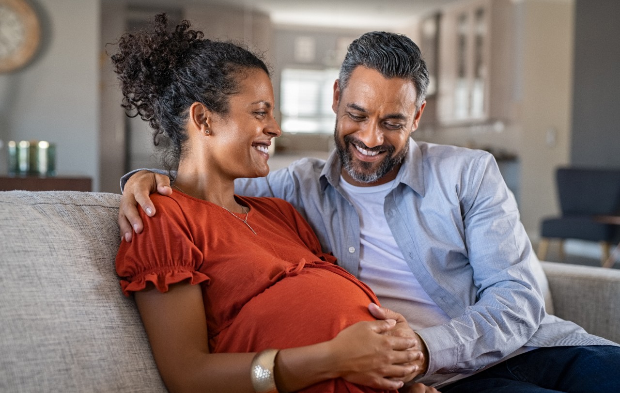 Pregnant women and man sitting on couch together