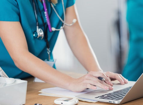 Picture of a nurse's hands using a laptop at work.